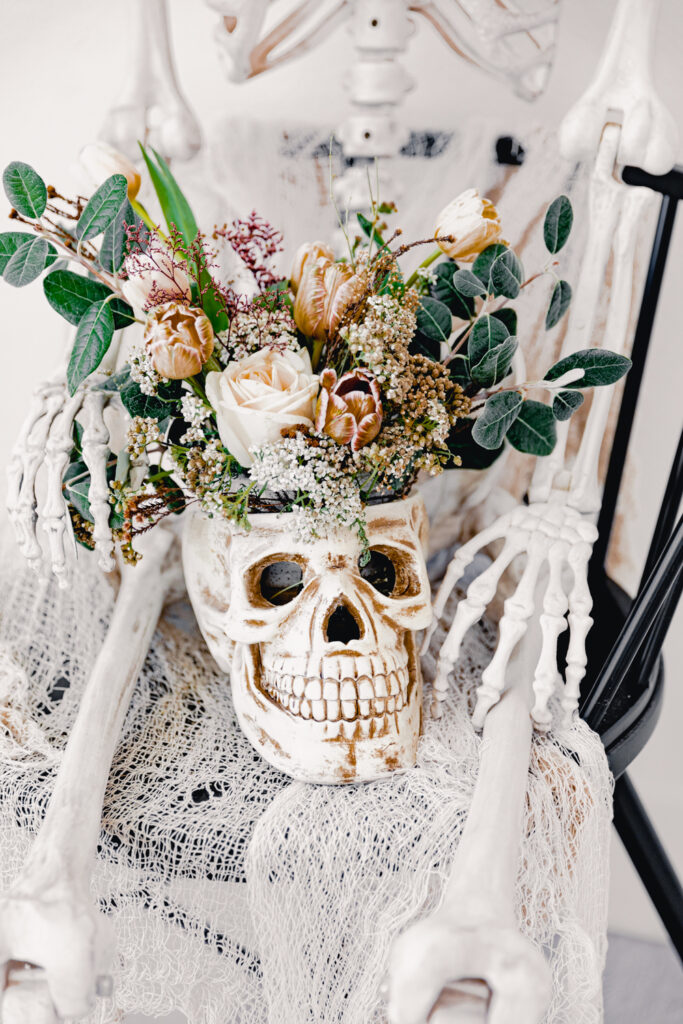 12 Stunning Halloween Florals to Inspire a Spooky Event / a skull vase with classic white flowers and lush greenery